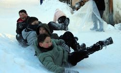 Mahalle yolunu kızak pistine çeviren çocuklar karın tadını çıkardı