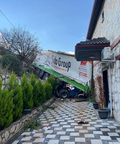 Antalya'da şarampole devrilen tırın bir eve çarparak durabildiği kazada sürücü yaralandı