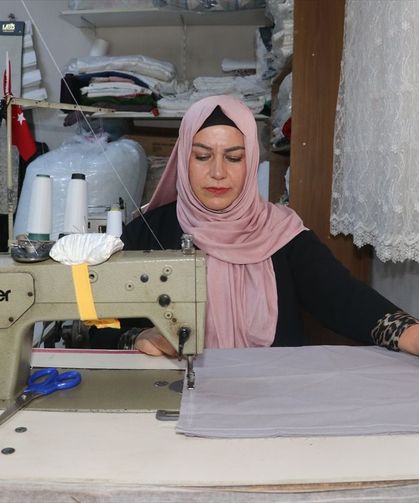 Kadın muhtar mahallelinin hem derdini dinliyor hem terziliğini yapıyor