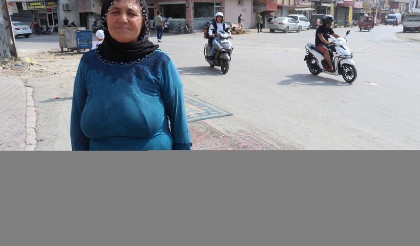 Adana'da tozdan rahatsız olan kadın yoldaki çukurları halıyla kapattı